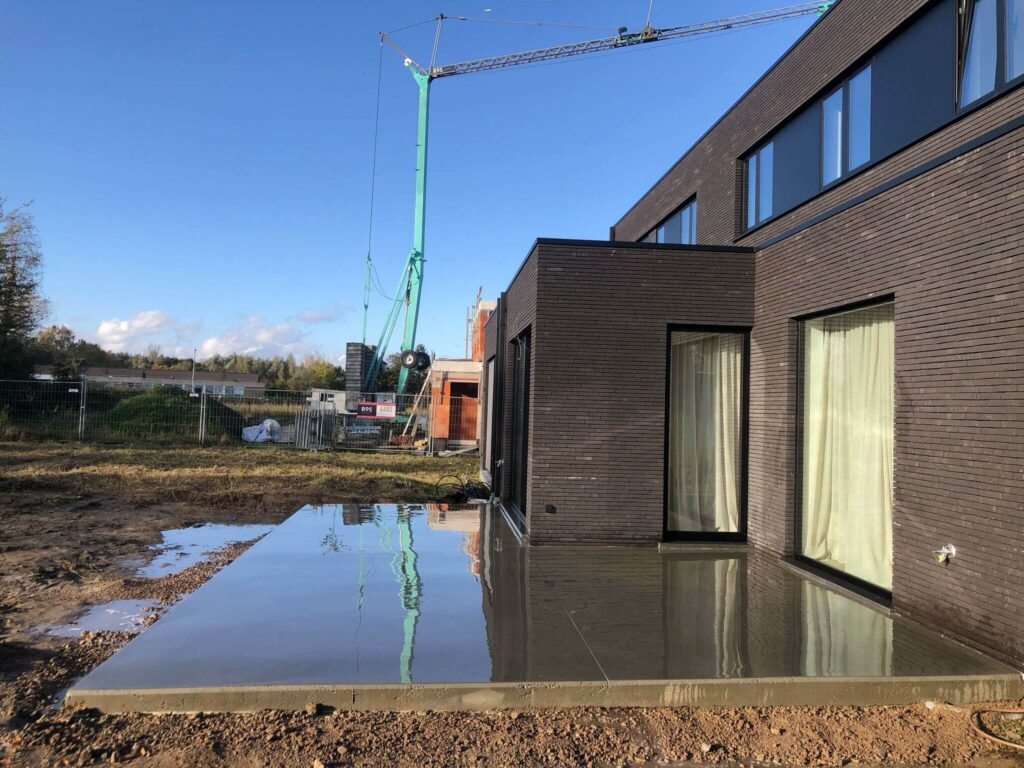 Groot spiegelend betonnen terras aan moderne woning